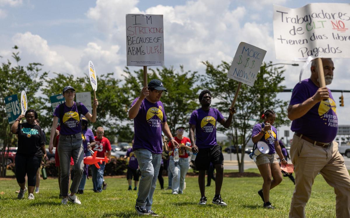 Airport service workers hold up picket signs during a rally near the intersection of Wilkinson Boulevard and Josh Birmingham Parkway in the file photo from last year. The Service Employees International Union is asking the city to approve an ordinance to increase pay for airport workers.