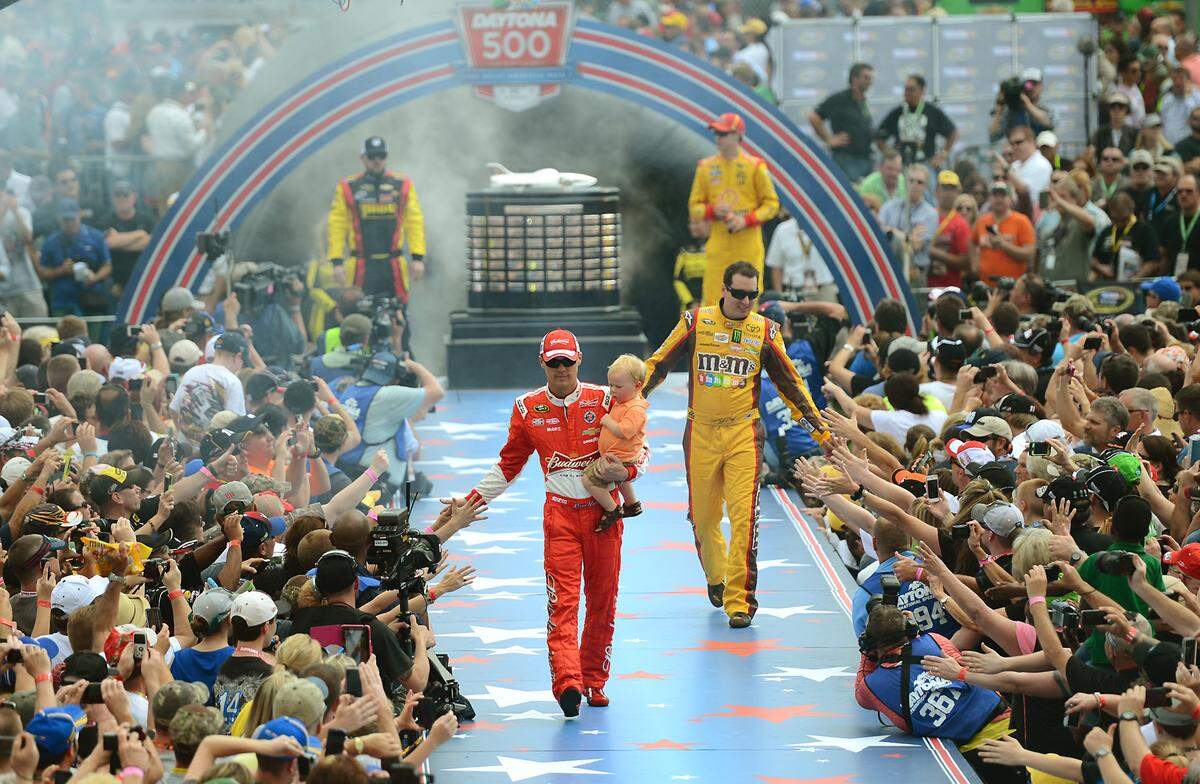 NASCAR Sprint Cup Series drivers Kevin Harvick (4) and Kyle Busch (18) are introduced during driver introductions for the Daytona 500 at Daytona International Speedway on Sunday, February 23, 2014. The race was stopped due to rain. Harvick is carrying his son, Keelan Harvick. 