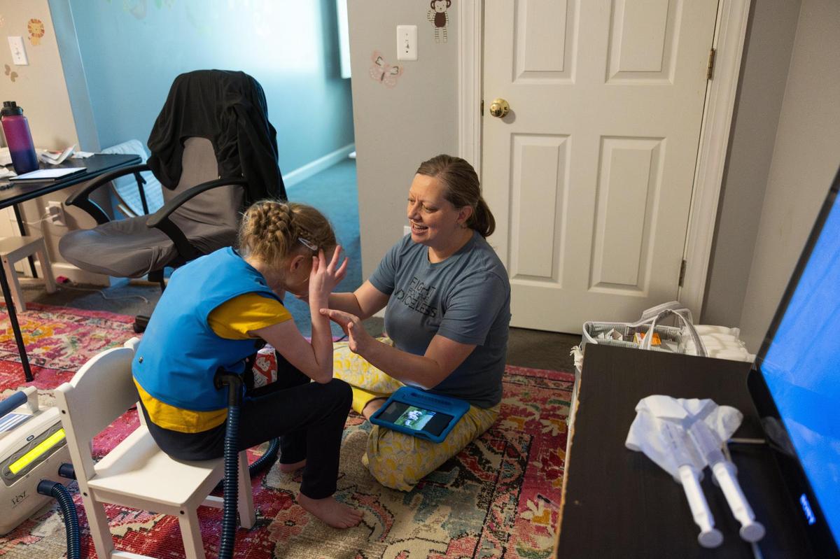 Stacy Staggs, talks to her daughter while she gets a daily medical treatment for her lungs in Charlotte, N.C., on Tuesday, April 11, 2025.