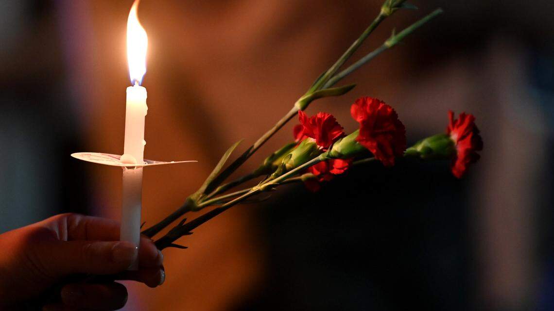 A community member holds a candle and carnations during a memorial service for Iryna Zarutska on Sept. 22 in Charlotte.
