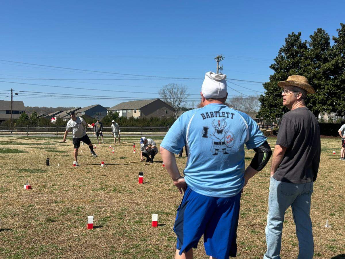 Nick Bartlett and Mike Horengic stand as they watch and strategize a game of Kubb at the North Carolina Kubb Tournament in Davidson.
