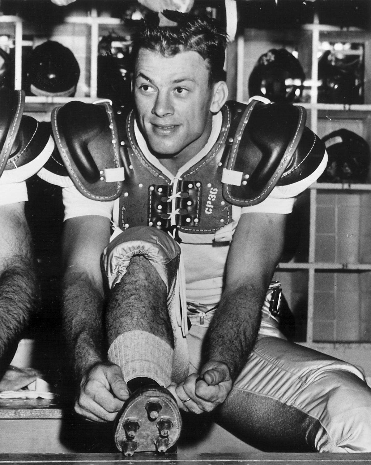 Charlie “Choo Choo” Justice laces up his cleats in the locker room. Justice finished runner-up for the Heisman Trophy in both 1948 and 1949.