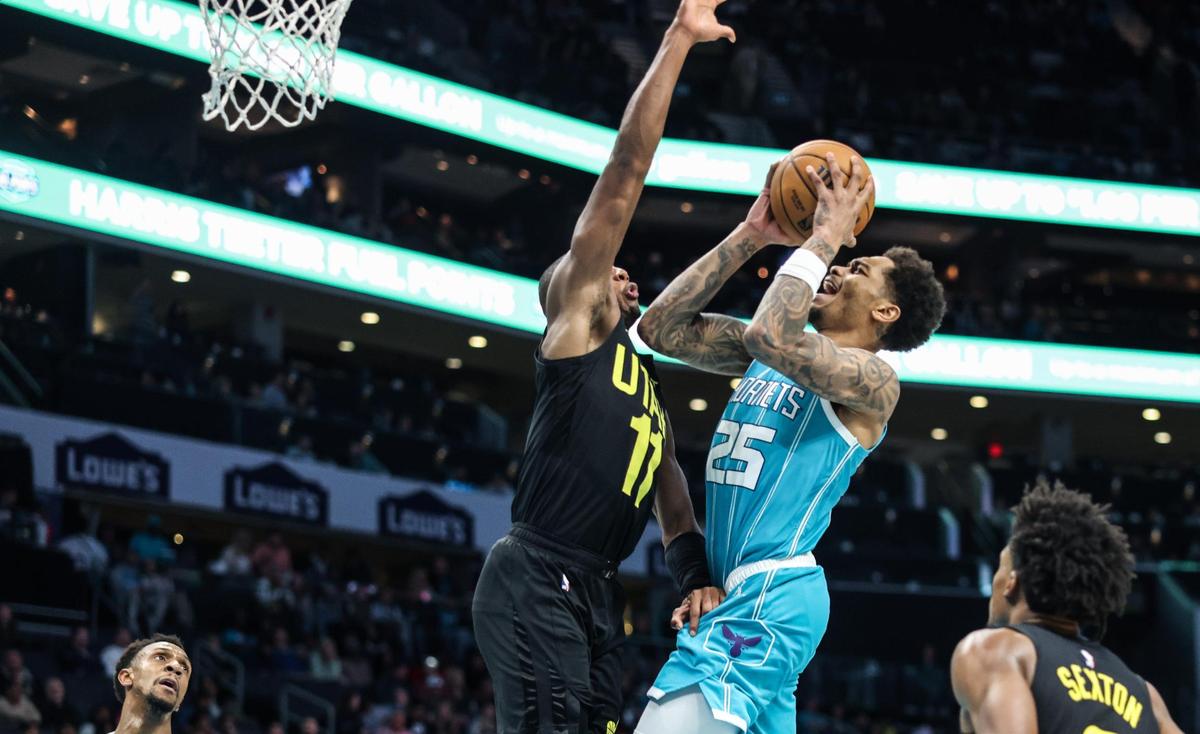 Charlotte Hornets forward P.J. Washington, right, shoots past Utah Jazz guard Kris Dunn at the Spectrum Center in Charlotte, N.C., on Saturday, January 27, 2024.