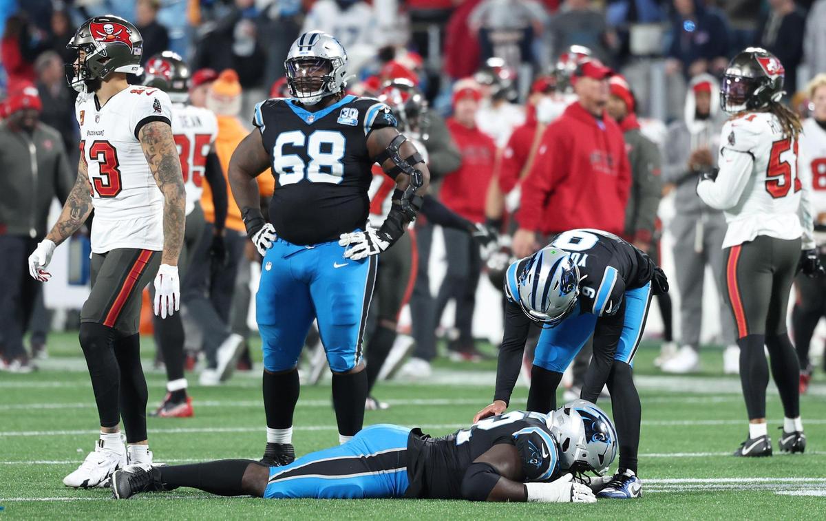 Carolina Panthers quarterback Bryce Young consoles tackle Taylor Moton as he lays on the field after being unable to recover a fumble by running back Chuba Hubbard during overtime against the Tampa Bay Buccaneers at Bank of America Stadium in Charlotte, NC on Sunday, December 1, 2024. The Buccaneers defeated the Panthers 26-23. At left guard Damien Lewis looks on.
