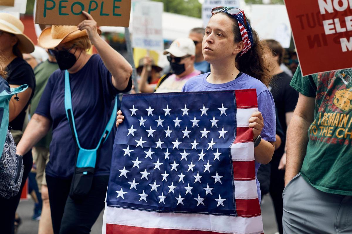 A woman holds her American flag tightly as she listens to speeches on Central Avenue in Charlotte Saturday during an anti-Trump protest.