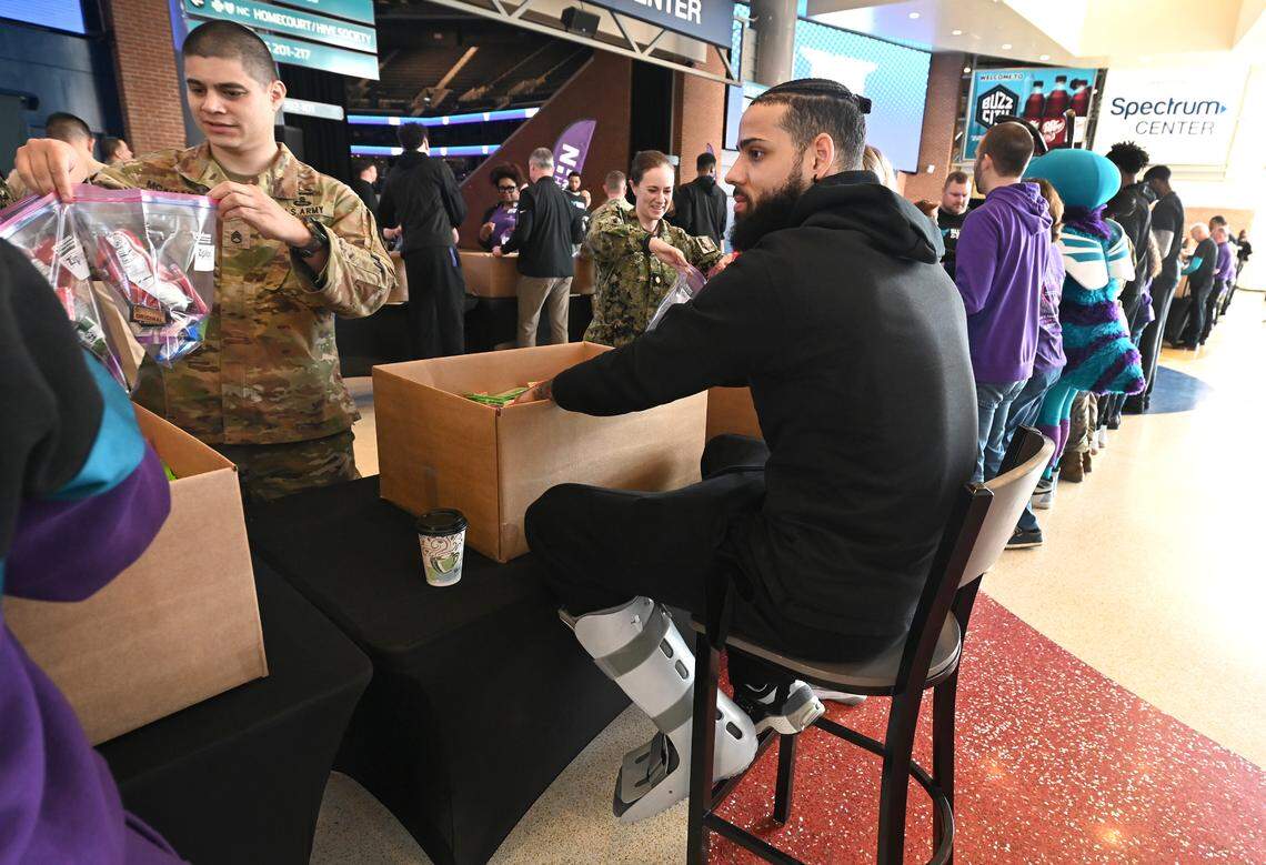 Charlotte Hornets guard/forward Cody Martin, center, wears a walking boot on his left leg during the team and Novant Health’s Military Care event at Spectrum Center on Monday, March 4, 2024.