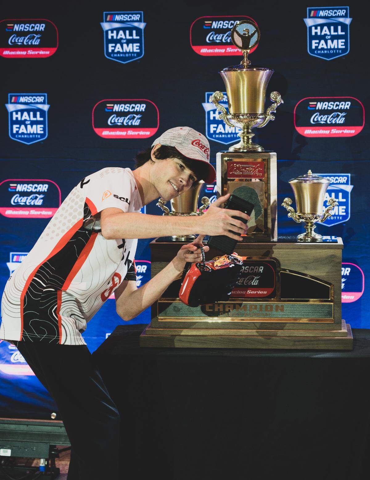 Casey Kerwan, right, poses with the 2022 eNASCAR series championship trophy on Tuesday, Oct. 25, 2022 in the NASCAR Hall of Fame in Charlotte.