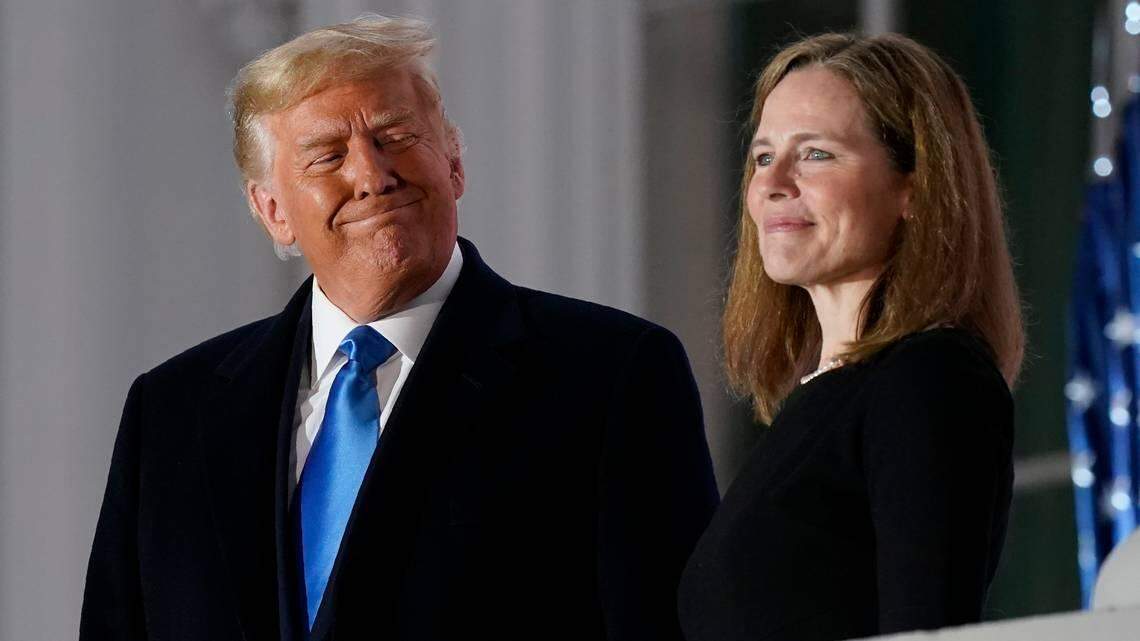 President Donald Trump and Amy Coney Barrett stand on the Blue Room balcony after a prime-time Supreme Court swearing-in event on the South Lawn at the White House. Barrett was confirmed Monday by the Senate in a 52-48 virtual party line vote.