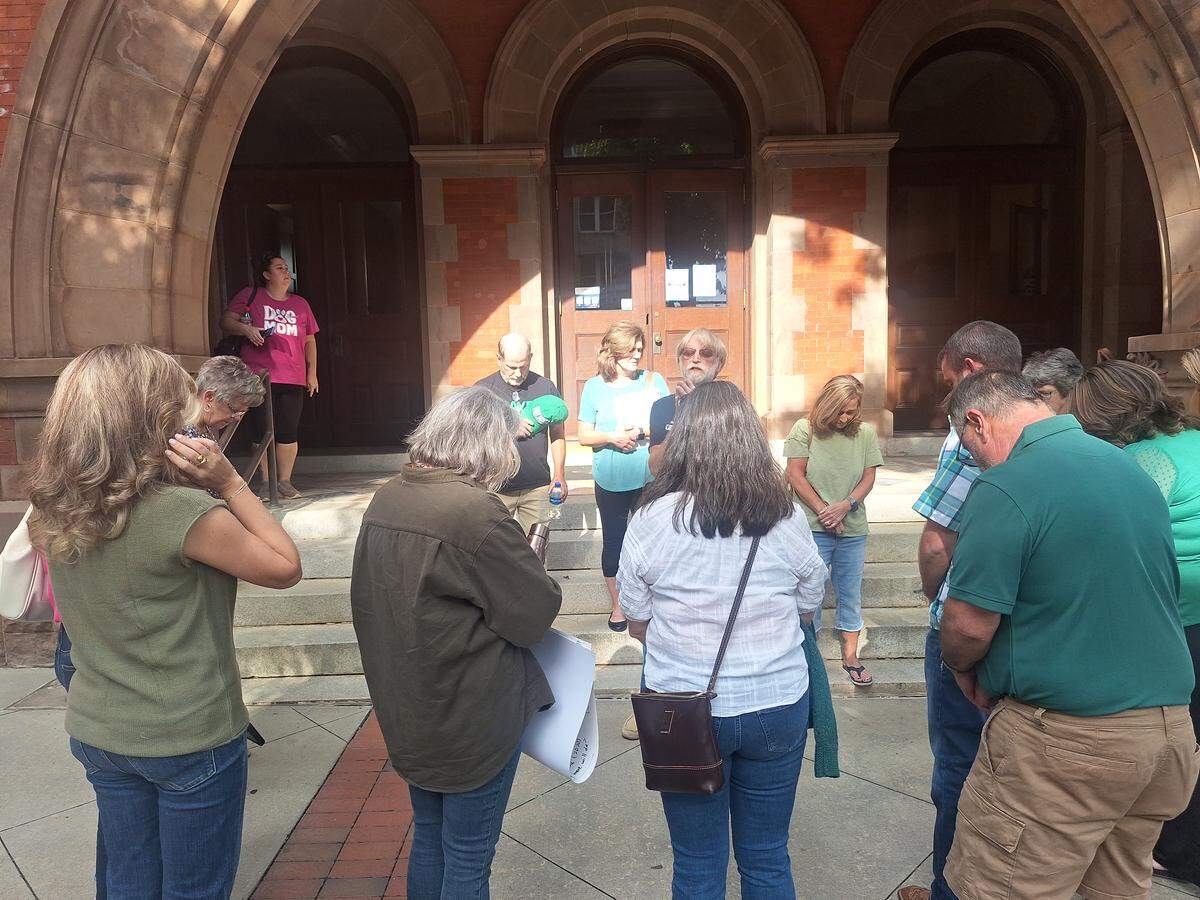 Jeff Tucker, who lives within a mile of a proposed data center on Stamey Farm Road in western Iredell County, leads fellow concerned neighbors in prayer outside Statesville City Hall before a hearing on the project Tuesday night, Aug. 26, 2025..
