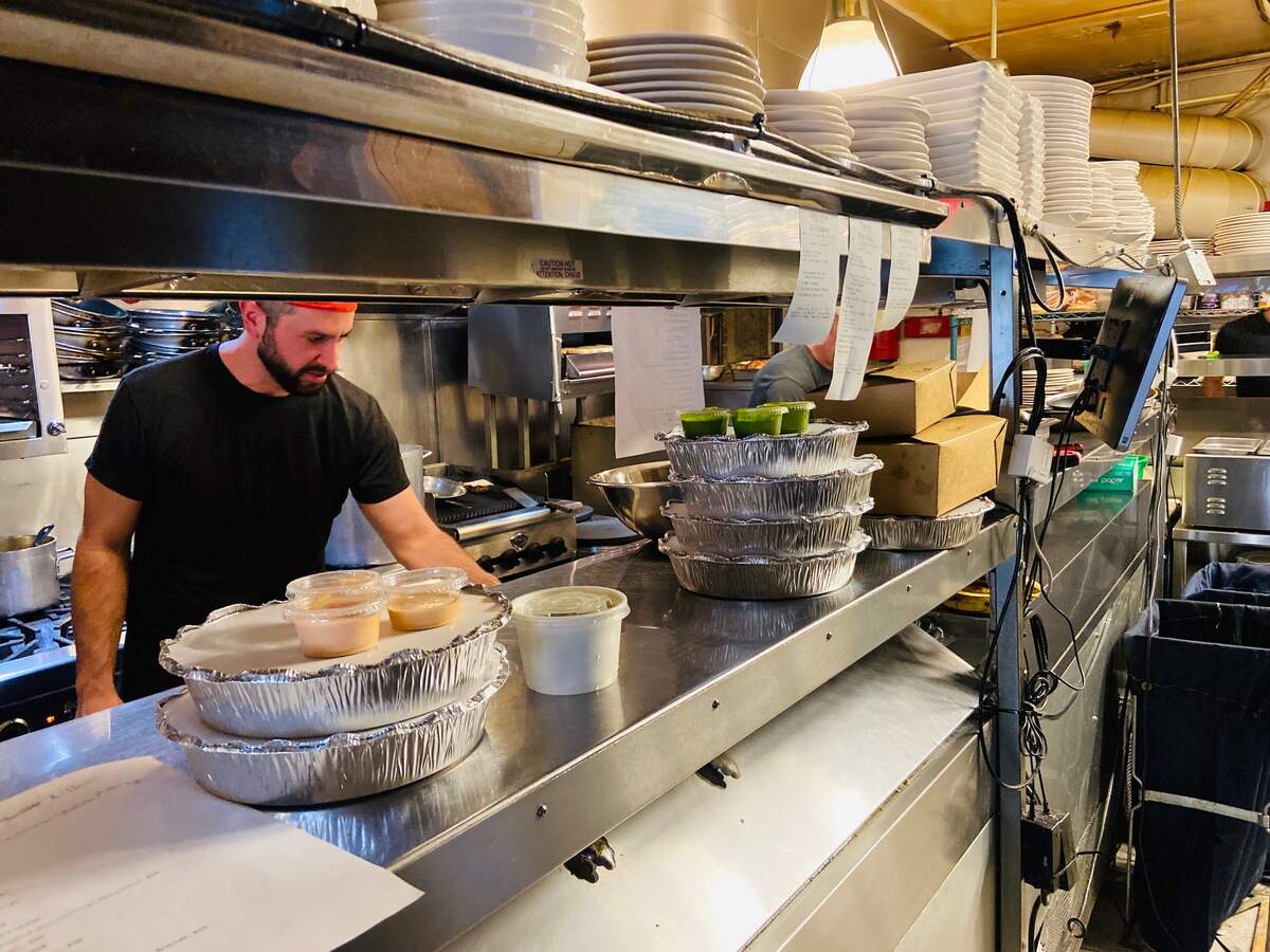 An employee prepares takeout orders at Crepe Cellar/Growlers.