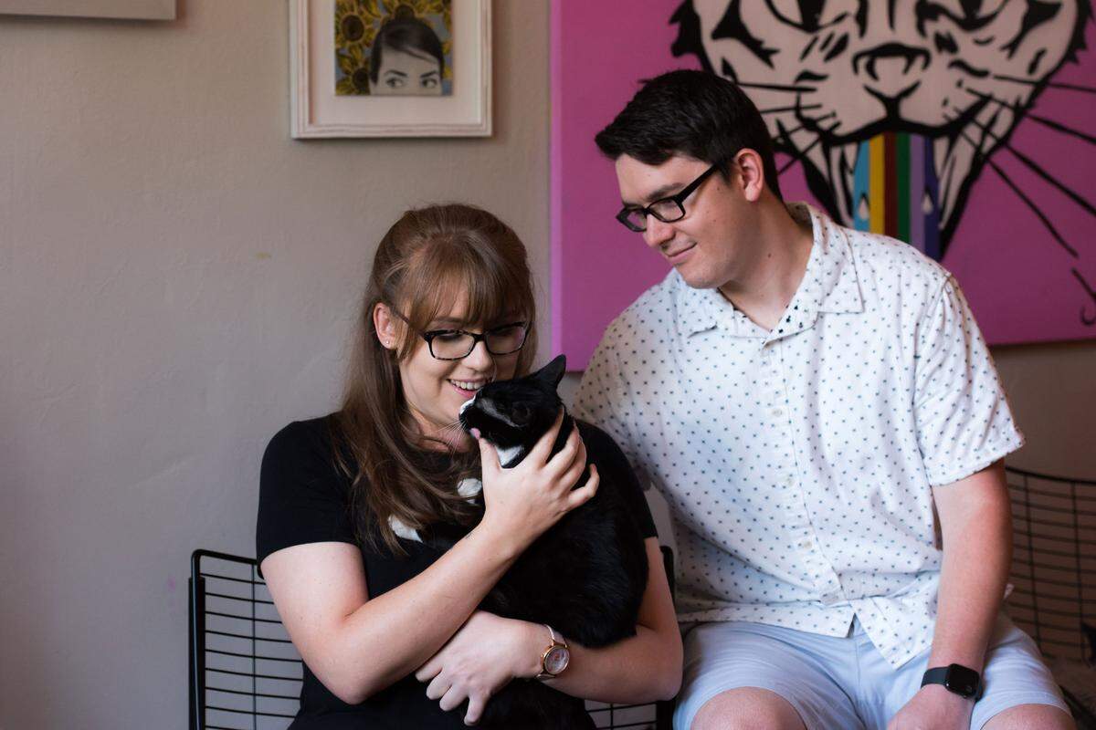 Mac Tabby Cat Cafe kitten Hayden cuddles with Leanan Gardener and Sean Pitchford.