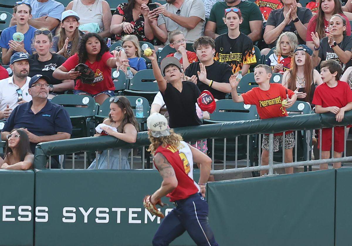 A young fan reaches up to catch a ball tossed into the stands by Texas Tailgaters left fielder Caden “Peanut” Green during action against the Firefighters at Truist Field in Charlotte, NC on Thursday, June 4, 2026. Banana Ball action returned to the Queen City with the Texas Tailgaters battling the Firefighters.