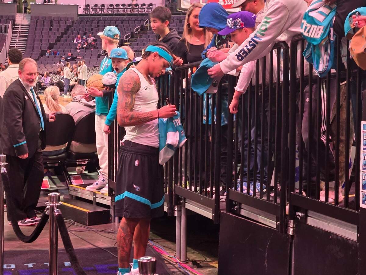 Charlotte Hornets guard Tre Mann signs autographs for fans before their game against Oklahoma City on Dec. 28, 2024.
