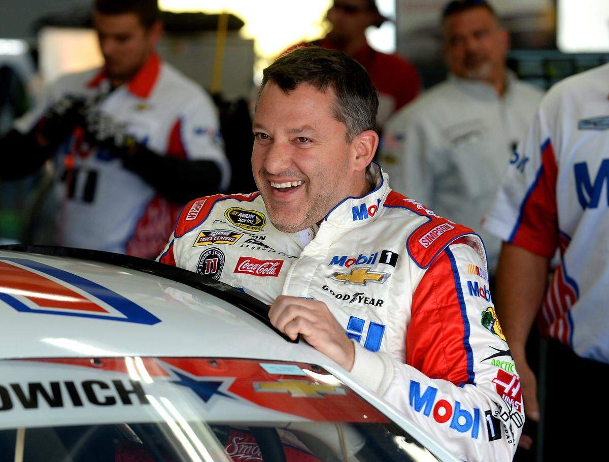 NASCAR Sprint Cup Series driver Tony Stewart laughs with members of his team as he climbs into his car for practice at Charlotte Motor Speedway on Thursday, May 26, 2016.
