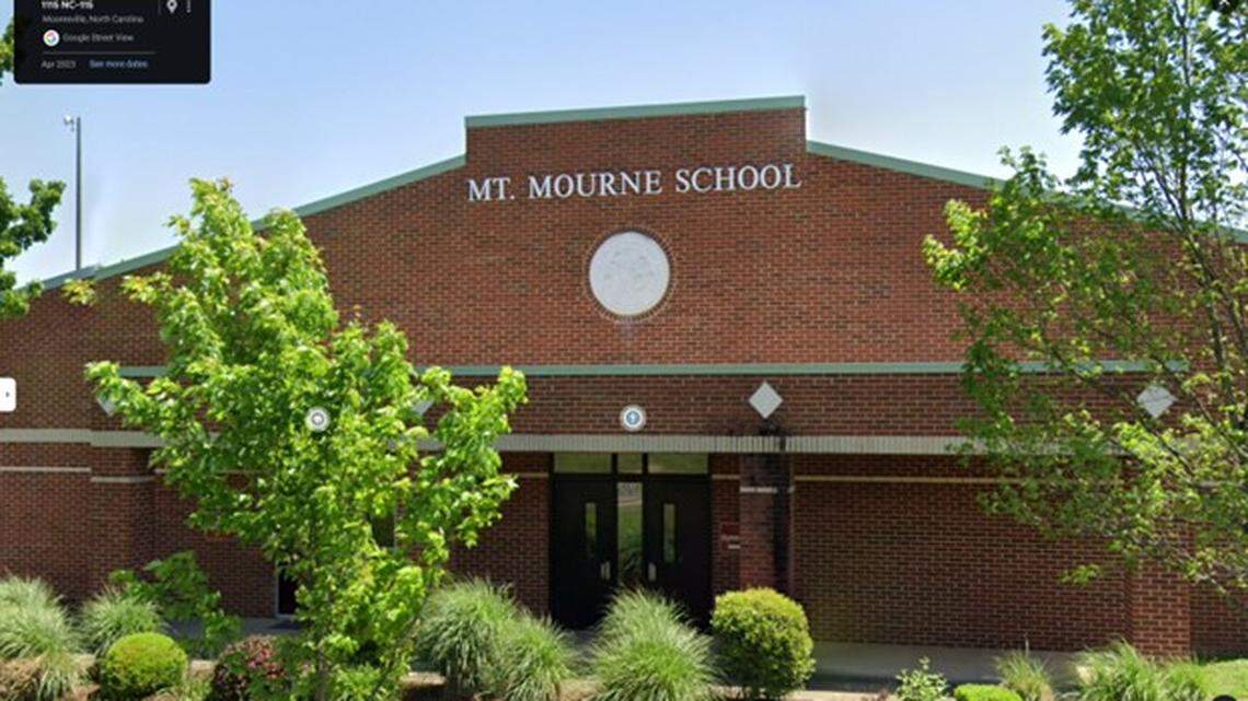 An old red brick school surrounded by green foliage. 