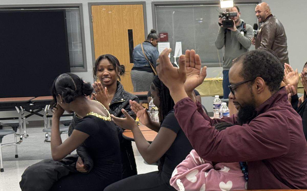 West Charlotte High band director Adam Sobers, right, applauds along with students after the announcement of the $10,000 gift.