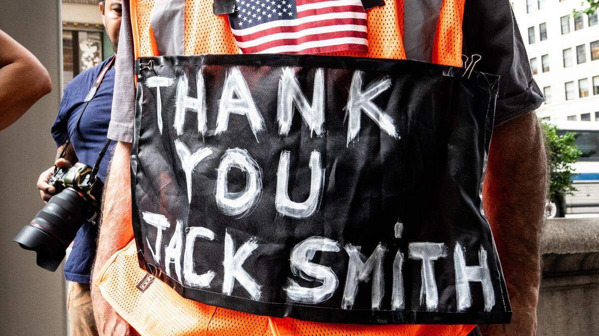 A man wearing a vest with a sign saying “Thank you Jack Smith” at an August 2023 protest outside Trump Tower in New York City.