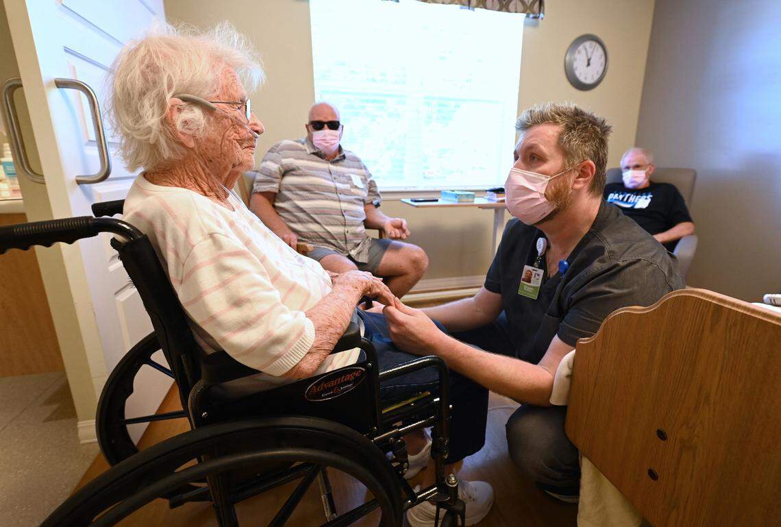 CNA Sloan Rollins, right, checks on Willie Miller, a 94-year-old resident of the Abernethy Laurels nursing home in Newton, N.C. Miller’s sons, seated in the background, look on.