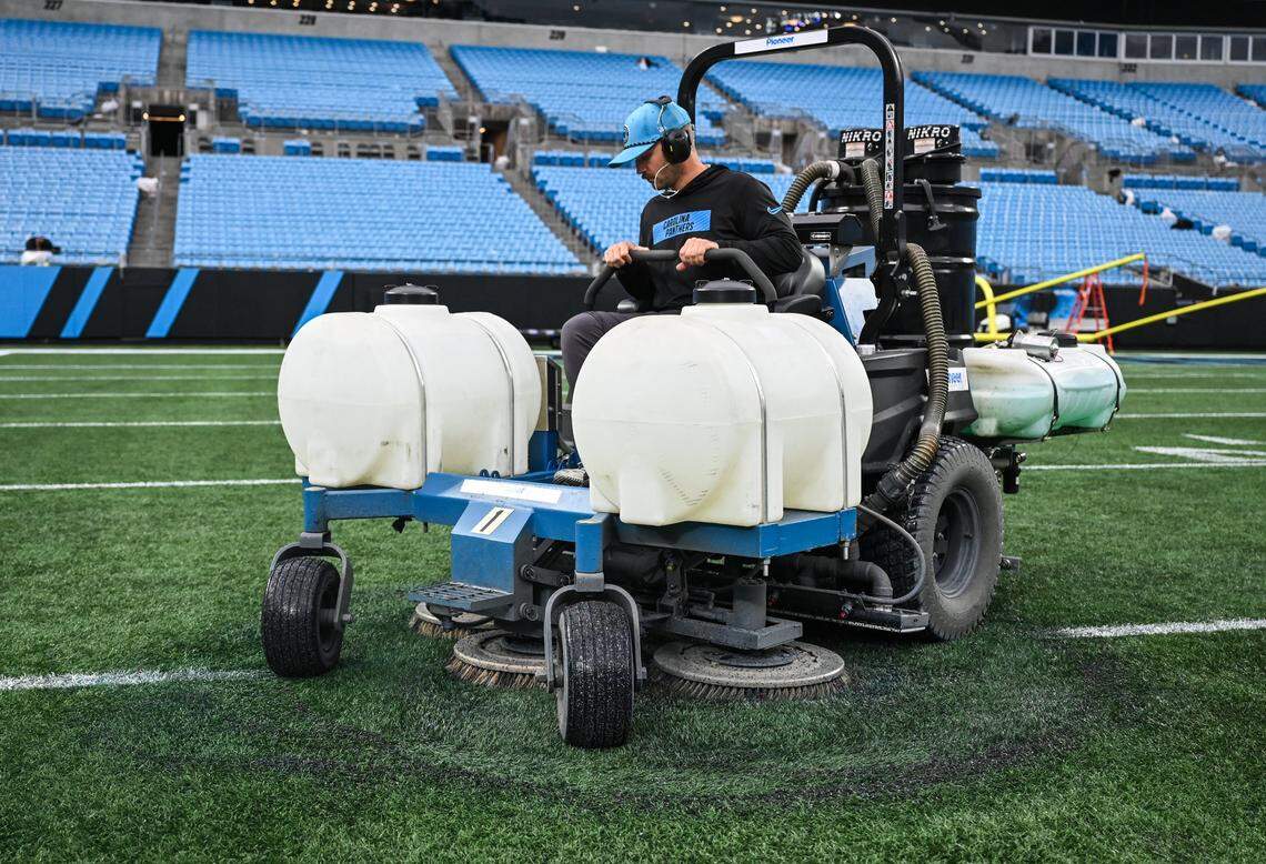 A member of the stadium operations crew works diligently to start scrubbing paint off the field from an NFL game and prepping it to be painted for Tuesday night's MLS game at Bank of America Stadium in Charlotte, NC on Sunday, October 26, 2025.