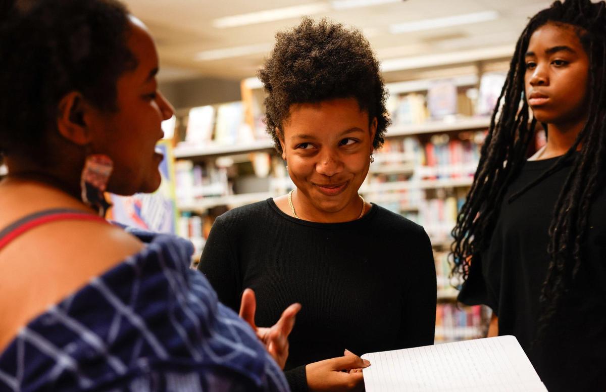 Naomi Rivers, 14, center, smiles at librarian Alyx Reid, who leads Inkspill writing club.