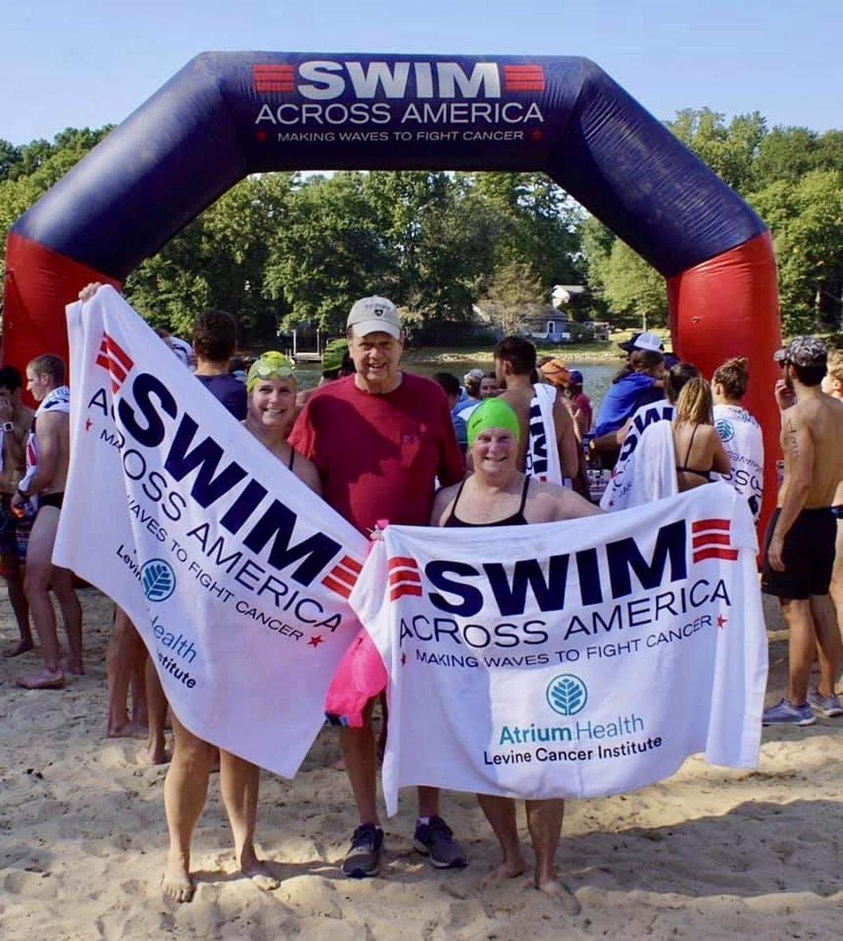 Katie Kalka (left) and her mother, Niki Lallande (right), pose for a photo before a recent Swim Across America event in Charlotte. Kalka swims for her father, Joe Lallande (center), who died of cancer in 2021.