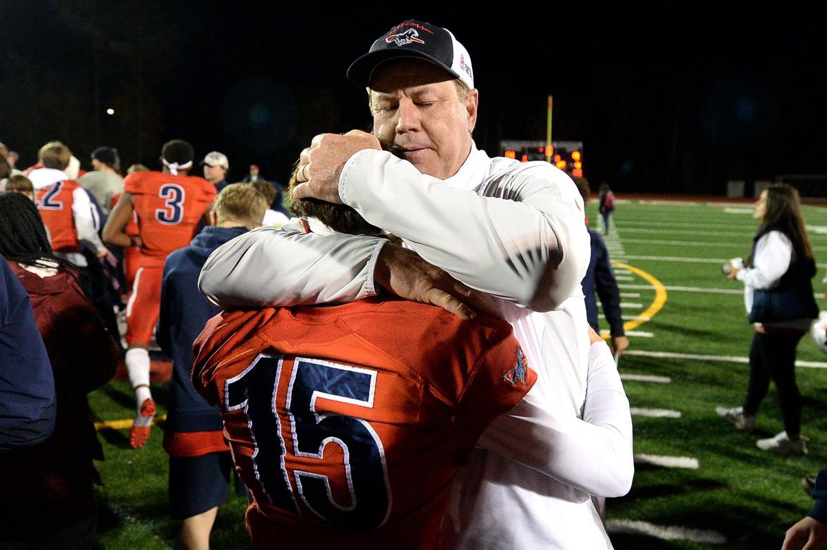 Providence Day Chargers head coach Chad Grier hugs wide receiver Nate Abraham following the teamÕs 14-9 victory over Rabun Gap at Providence Day School in Charlotte, NC on Friday, November 19, 2021. The Chargers defeated Rabun Gap to win the NCISAA boys state championship game.