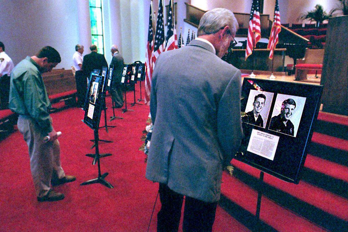 Stan Norket, the stepfather of slain police Officer John Burnette, reads the inscription below the photographs of Burnette (left) and his partner Anthony Nobles, at a Peace Officers memorial service for fallen officers Friday at First Baptist Church in Charlotte.