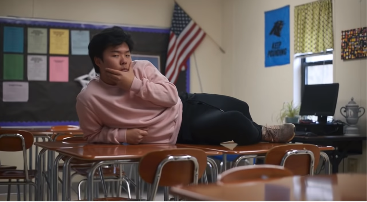 Kim lounges on desks during the video while rapping "Harvard, admit me, you know you want to."