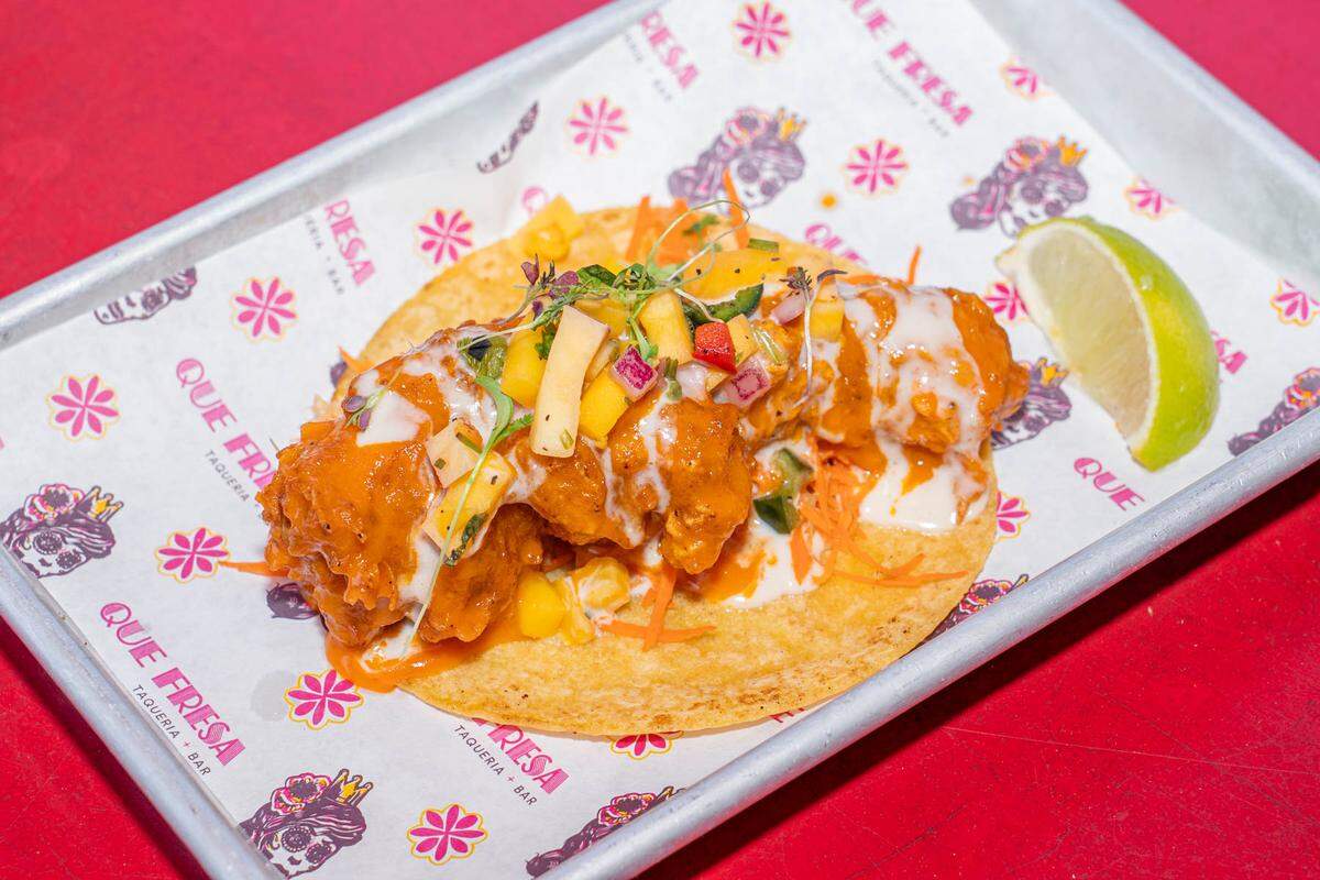 La Toxica taco at Que Fresa has fried chicken, mango buffalo sauce, carrot + celery slaw, blue cheese and crema mango salsa.