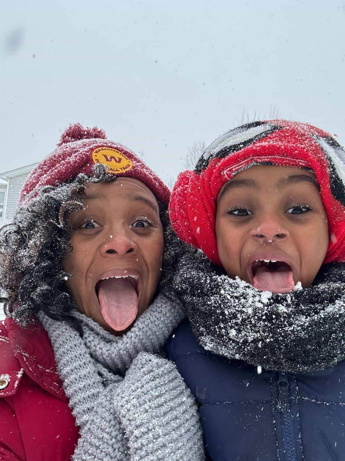 A mother and son in the Highland Creek are stick out their tongues in the snow on Saturday, January 31, 2026.