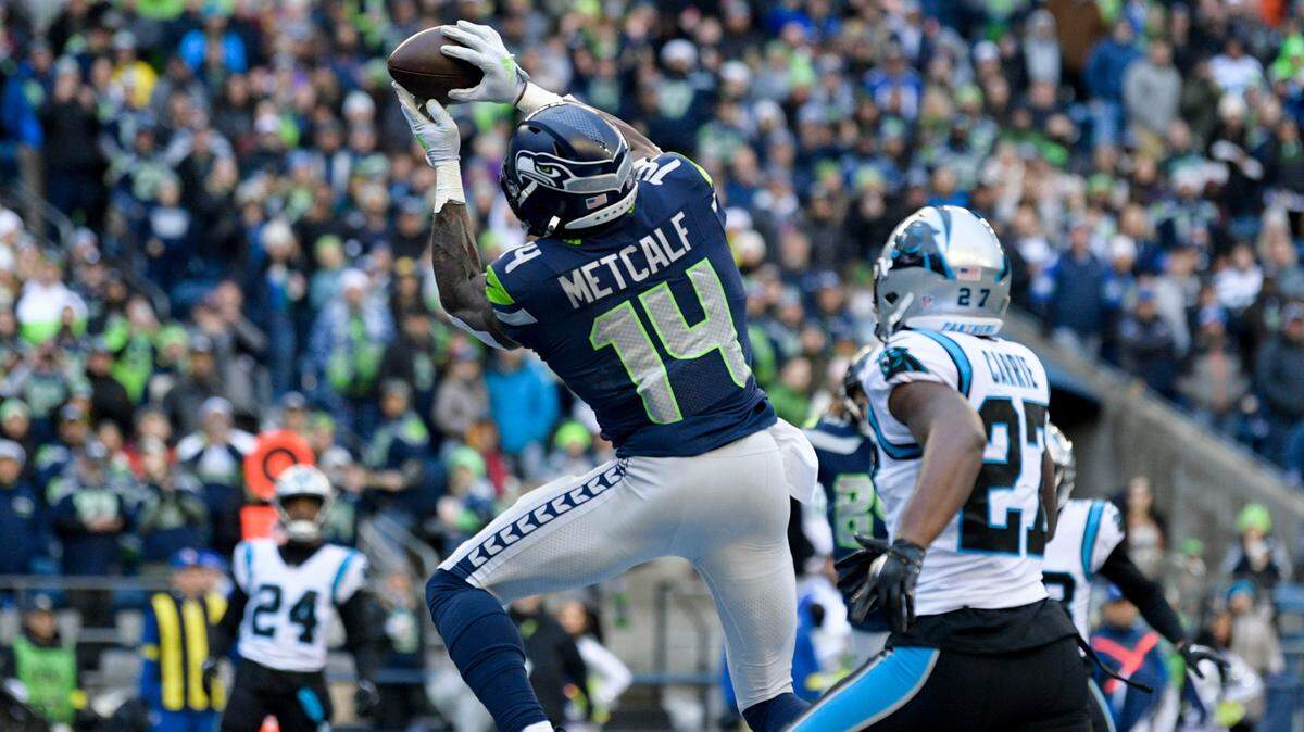 Seattle Seahawks wide receiver DK Metcalf (14) makes a touchdown catch against Carolina Panthers cornerback T.J. Carrie (27) during the first half of an NFL football game, Sunday, Dec. 11, 2022, in Seattle. (AP Photo/Caean Couto)