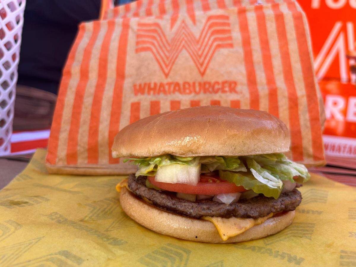 A Whataburger with cheese comes with tomato, lettuce, pickles, diced onions and mustard.