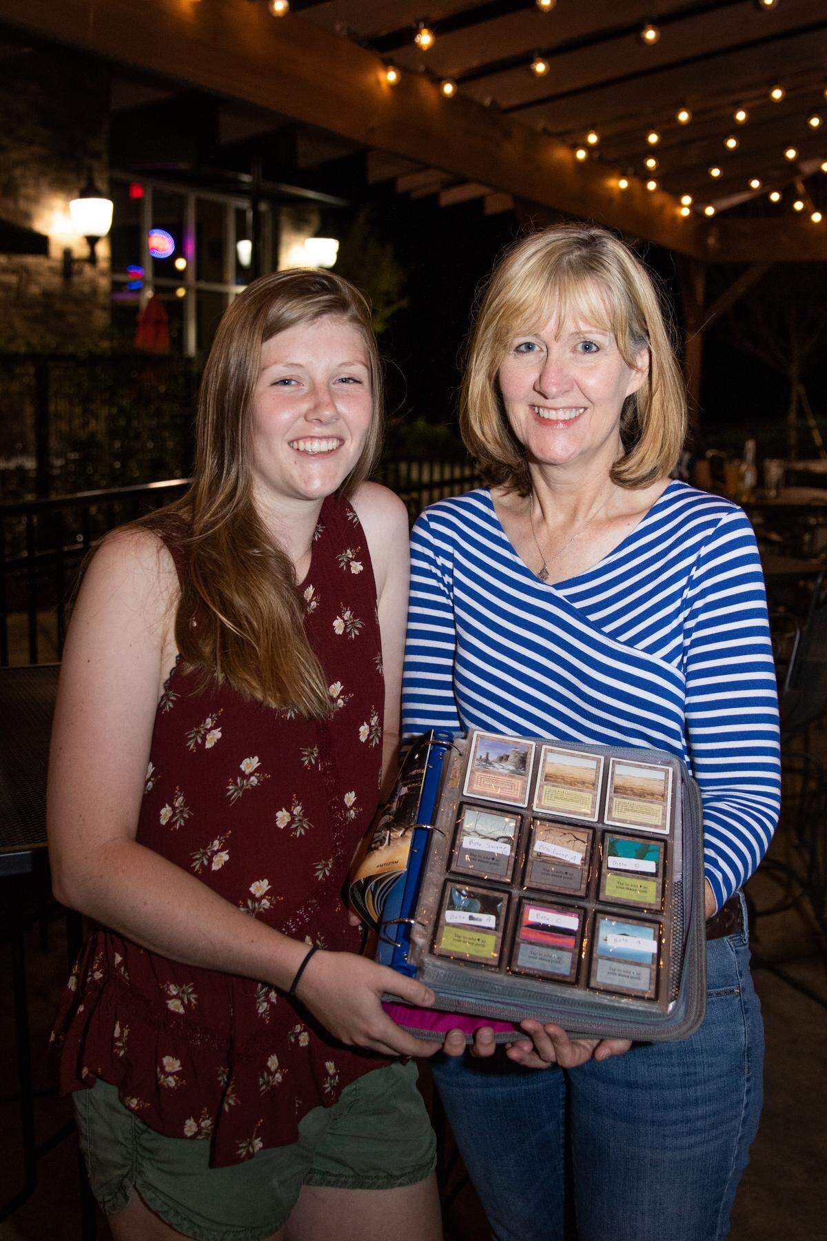 Kess Hendrix poses with her mom, Michele Hendrix, 52, while holding the “Magic The Gathering” cards they still own, which are worth between $300-$500 each.