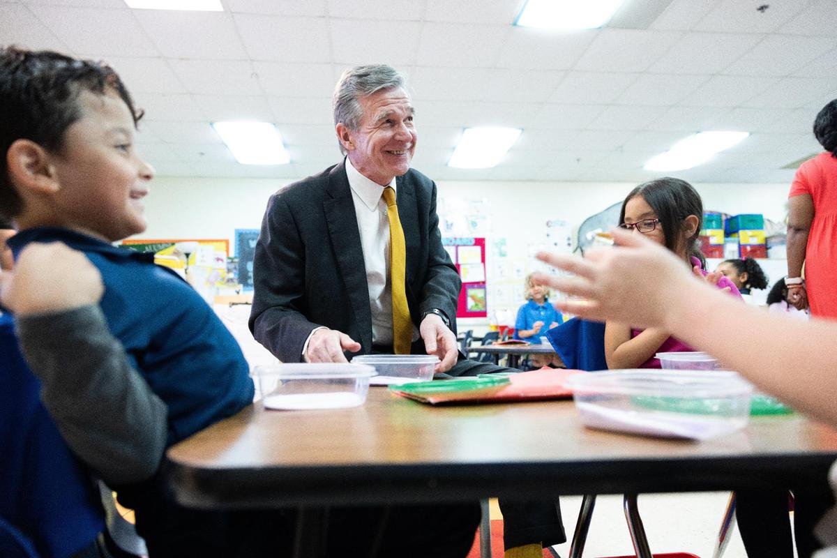 Gov. Roy Cooper visits with students as he tours Huntingtowne Farms Elementary School, a traditional public school in Charlotte, N.C., on May 24, 2023. Cooper vetoed legislation that would have changed who approves charter schools