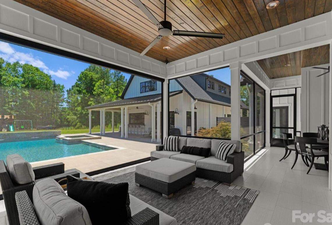 Outside the home is an in-ground pool, a covered dock and a pool house whose garage-style doors open to a pool deck, a full bar and a golf simulator screen, according to the listing.