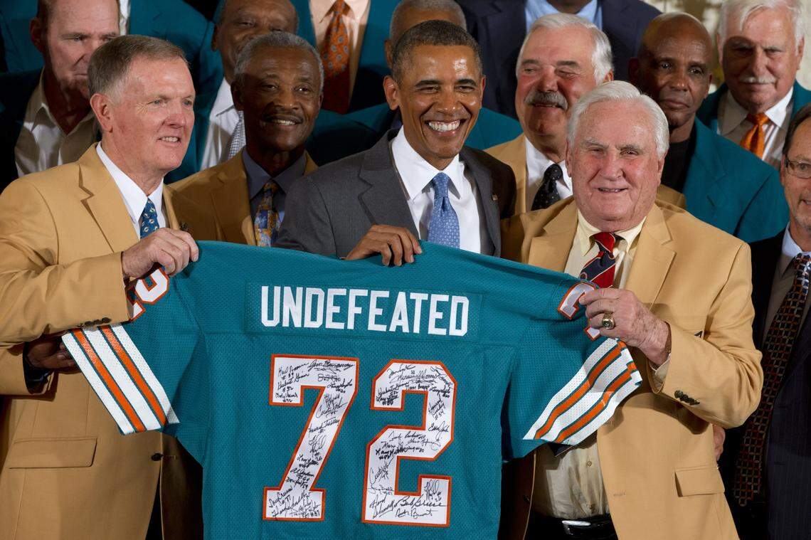 Former Miami Dolphin’s quarterback Bob Griese, left, holds a signed jersey with President Barack Obama and Hall of Fame coach Don Shula, forty-one years after their perfect football season as President Barack Obama honors the Super Bowl VII Champion Miami Dolphins in the East Room of the White House in Washington, Tuesday, Aug. 20, 2013. The 1972 Miami Dolphins remain the only undefeated team in NFL history.(AP Photo/Jacquelyn Martin)