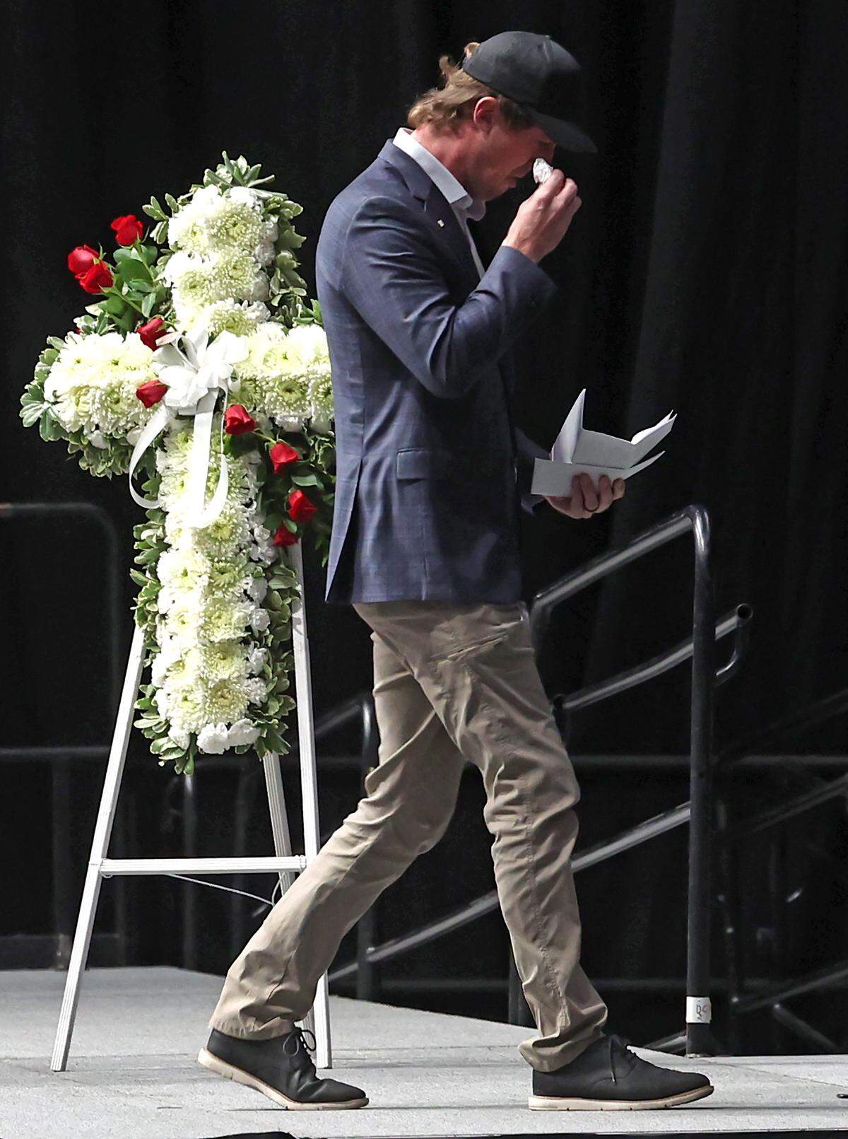 Garrett Mitchell wipes tears from his eyes as he exits the stage after speaking during a Gathering in Remembrance ceremony at Bojangles Coliseum in Charlotte on January 16, 2026. The ceremony, Gathering in Remembrance was held for the seven people who died in a plane crash on Thursday, December 18 in Statesville. Among the group was former NASCAR driver Greg Biffle.