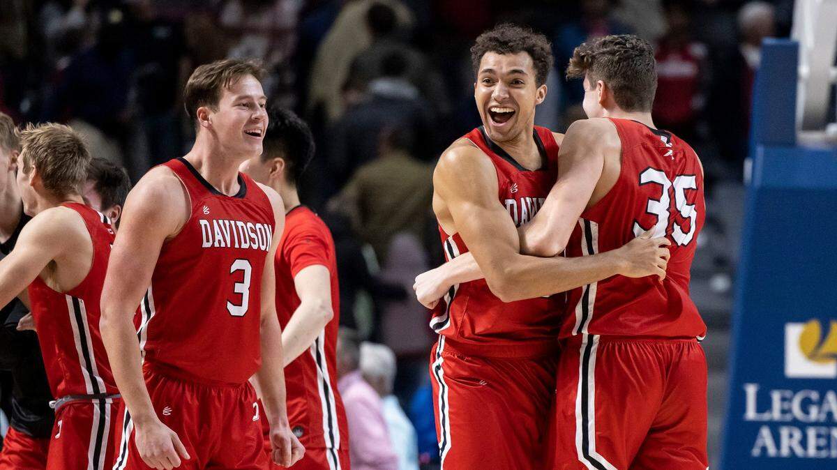 Davidson forward Nelson Boachie-Yiadom, center, hugs Davidson forward Luka Brajkovic (35) as they celebrate a 79-78 upset of Alabama on Dec. 21. The Wildcats entered A-10 play with a record of 10-2.