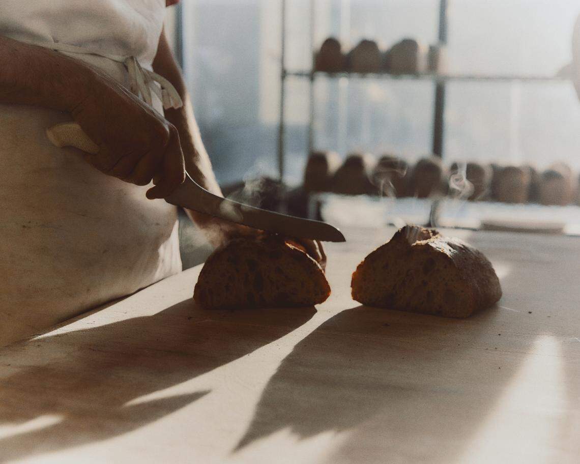 Cutting into a loaf of sourdough bread at Verdant.