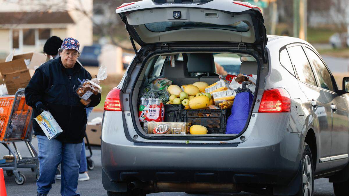 A volunteer carries food items to the trunk of a car for a Gastonia resident receiving free food at Mount Zion Restoration Church last month.