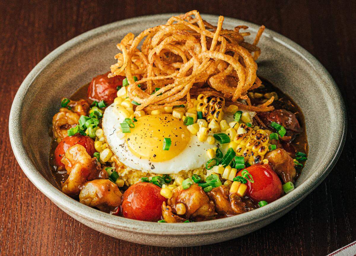 The shrimp and grits at Link & Pin is served with andouille, charred corn and a sunny side egg.