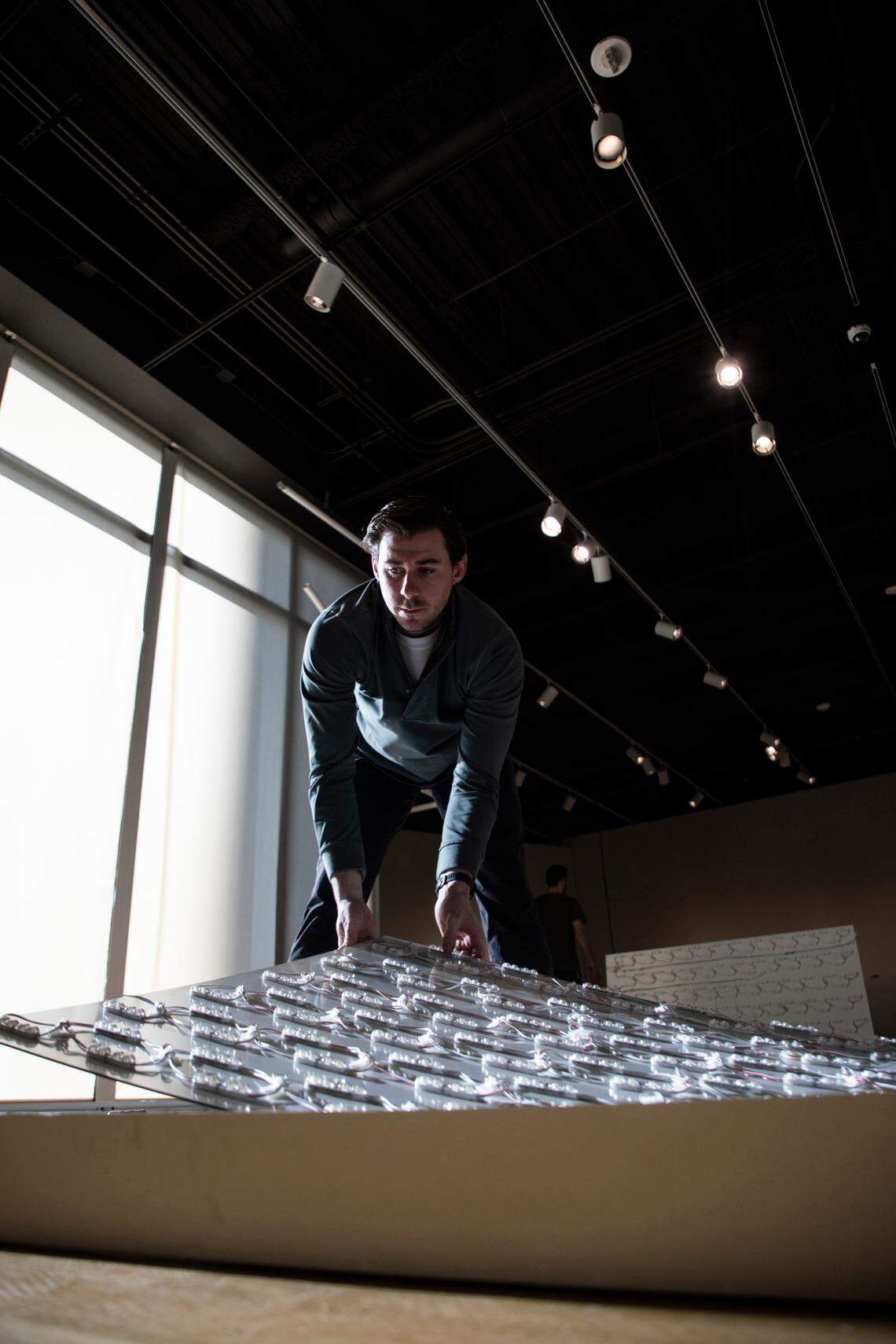 Zach Short lays down a light board on Jan. 20 that will get screwed onto a frame to display a photo of Pablo Picasso in the “Picasso Landscapes: Out of Bounds” exhibition.