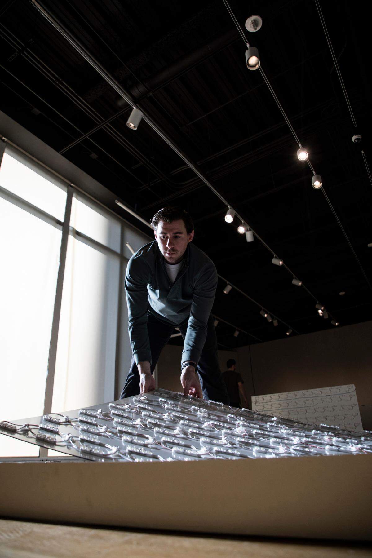 Zach Short lays down a light board on Jan. 20 that will get screwed onto a frame to display a photo of Pablo Picasso in the “Picasso Landscapes: Out of Bounds” exhibition.