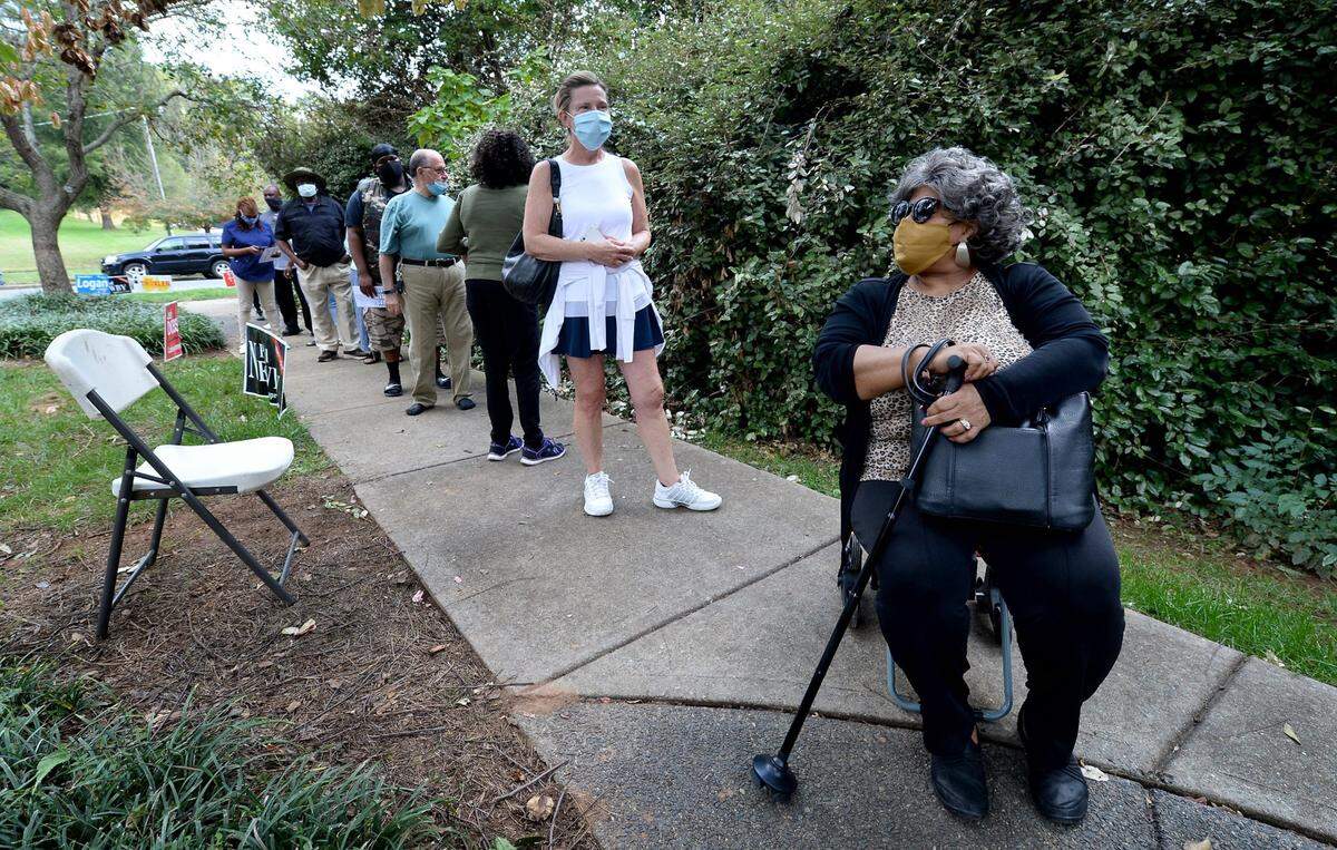 Nel James, right, brought a portable chair to wait in line with other voters at the West Blvd. library in Charlotte, NC on the first day of voting on Thursday, October 15, 2020.