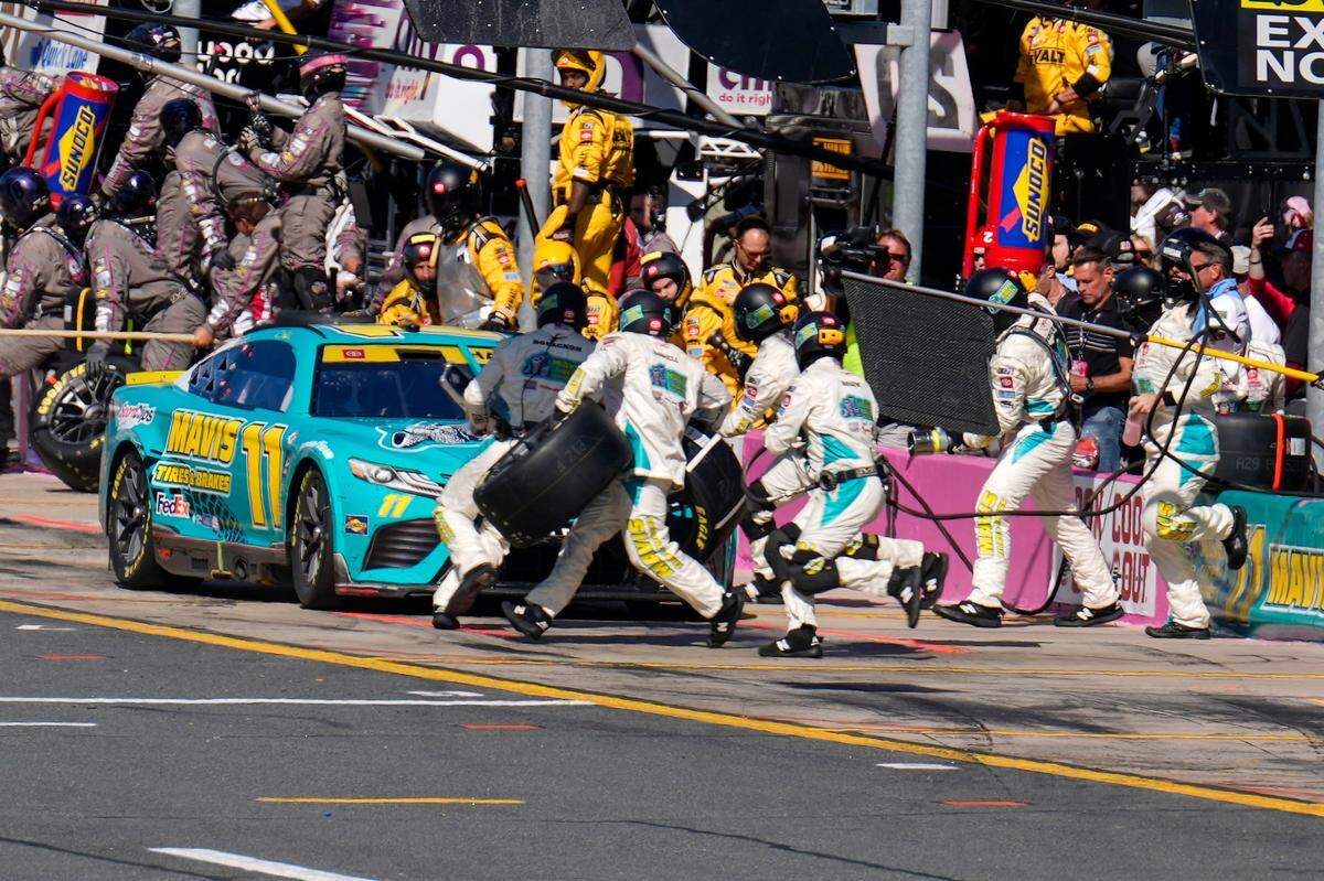 Oct 8, 2023; Concord, North Carolina, USA; NASCAR Cup Series driver Denny Hamlin (11) pit crew go to work during the Bank of America Roval 400 at Charlotte Motor Speedway Road Course. Mandatory Credit: Jim Dedmon-USA TODAY Sports