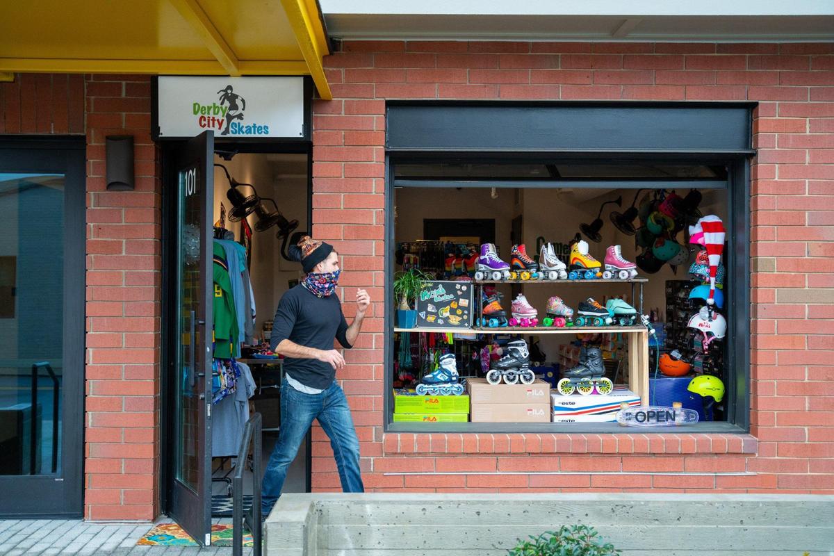 Derby City Skates owner Nicholas Connell walks in front of the garage-style storefront display window on Winnifred Street in South End, Charlotte.