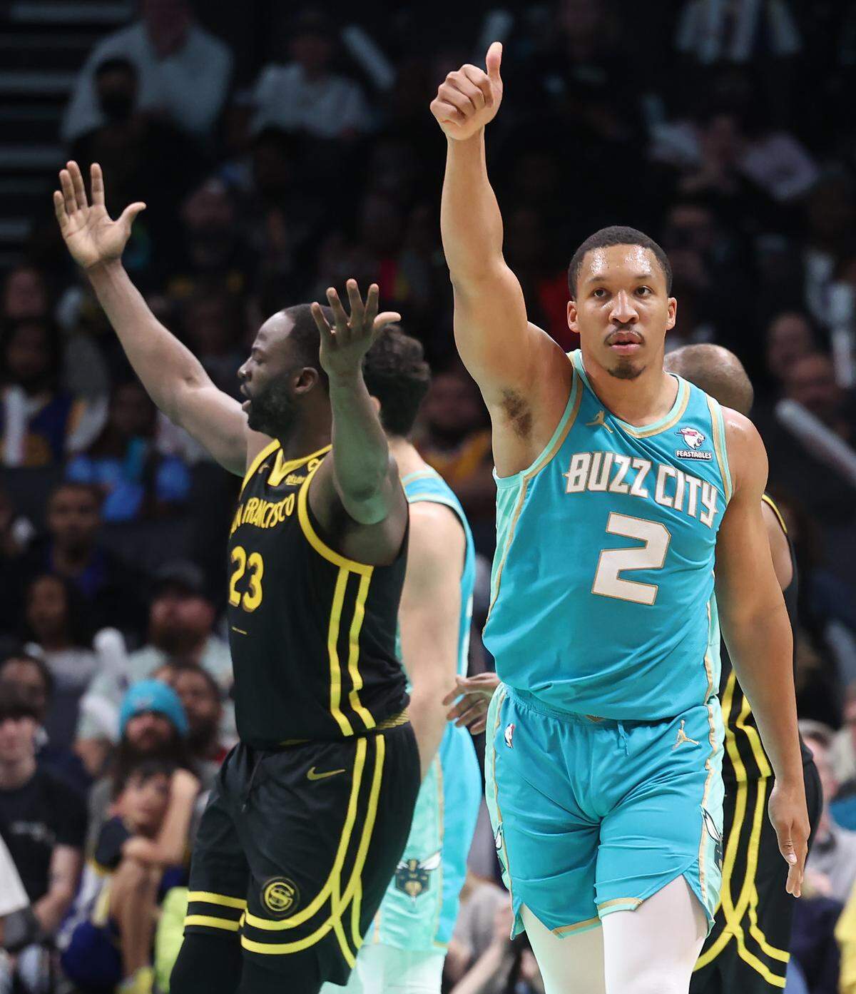 Charlotte Hornets forward Grant Williams, right, lifts his hand in the air as he celebrates drawing a foul on Golden State Warriors forward Draymond Green, left, during second-half action at Spectrum Center in Charlotte, NC on Friday, March 29, 2024. The Warriors defeated the Hornets 115-97.