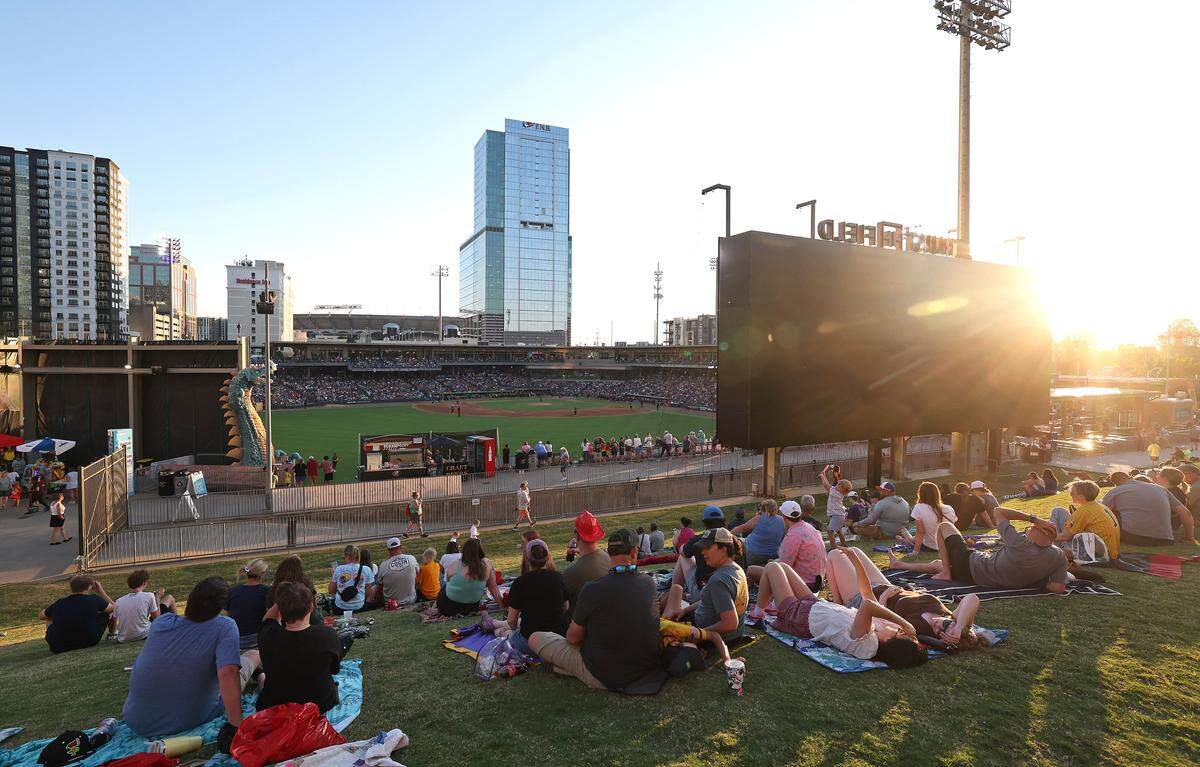 The evening sun bathes spectators relaxing on the hill overlooking Truist Field during the Texas Tailgaters vs Firefighters game on Thursday, June 4, 2026.