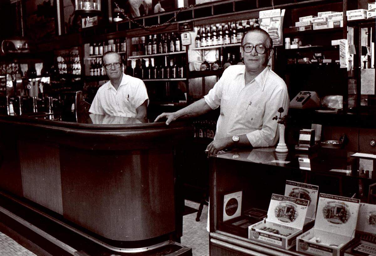 Tommy Kofinas (left) and John Tatsis opened Kofinas’ Snack Bar on West Trade Street in 1954 and closed in 1981. The building stood where the Carillon Building is today.  Kofinas and Tatsis died within five days of each other, in 2002.