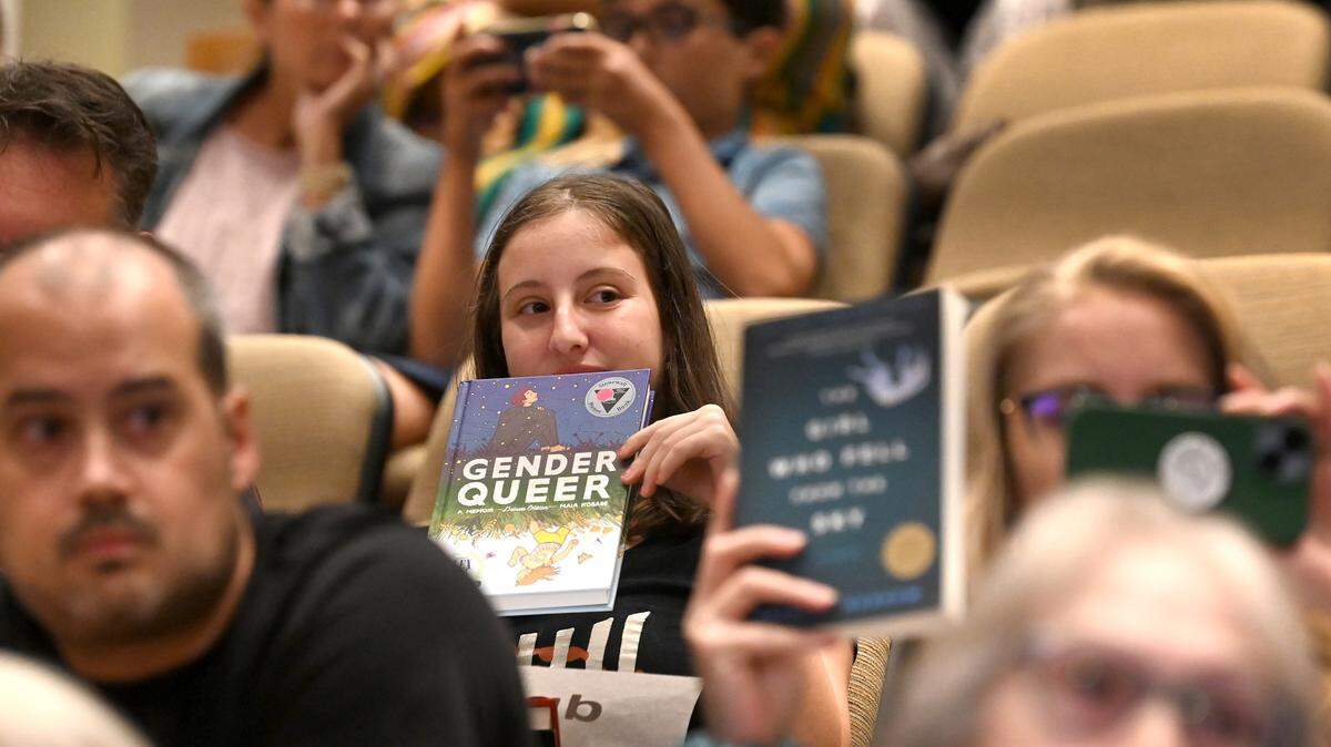 Audience members hold up signs as a speaker addresses the Charlotte Mecklenburg school board on Tuesday, August 22, 2023 at the Charlotte-Mecklenburg County Government Center. CMS is one of the first to pass policies to comply with Senate Bill 49.